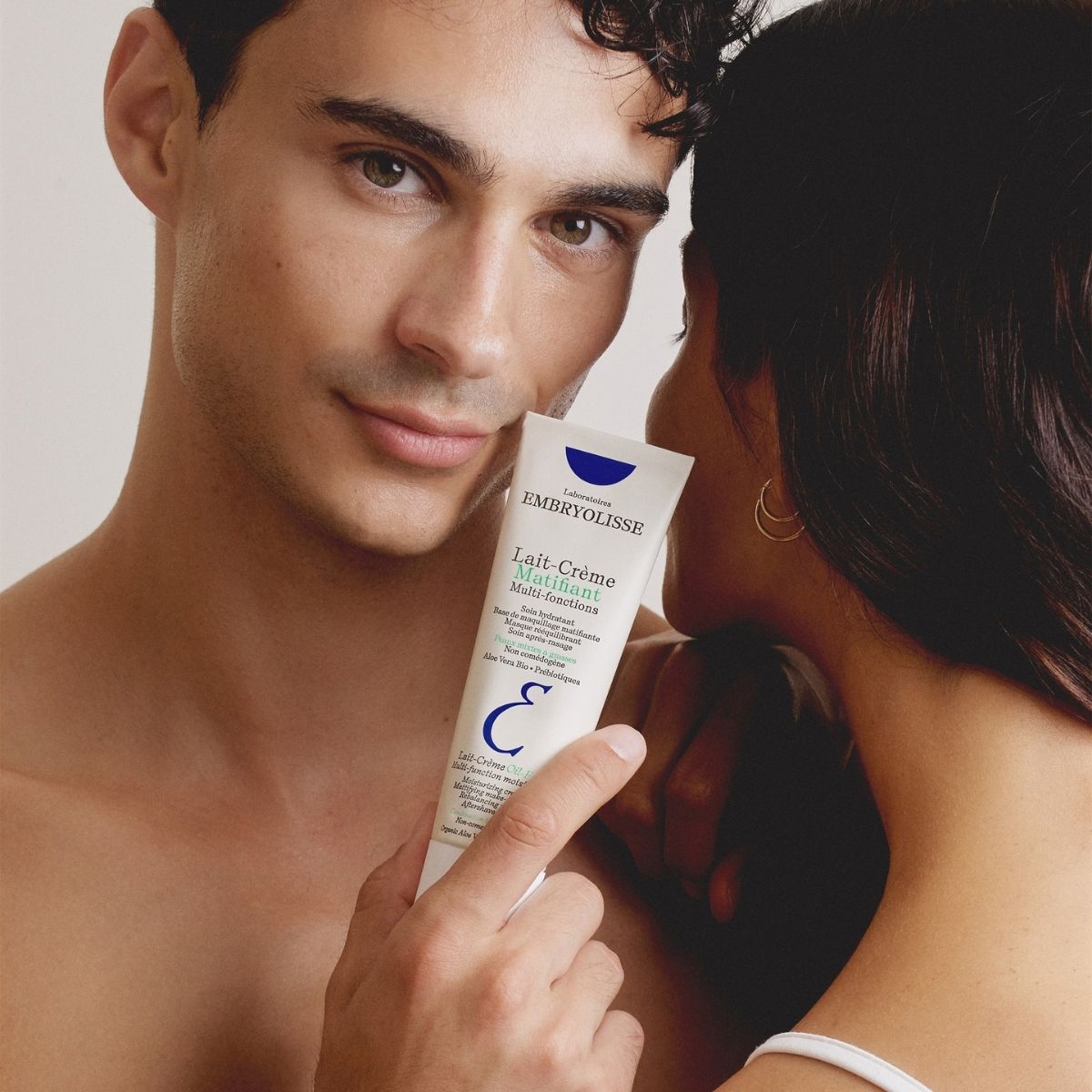 A man holds the Lait-Crème Oil-Free tube beside a woman, a moisturizer made for men and women