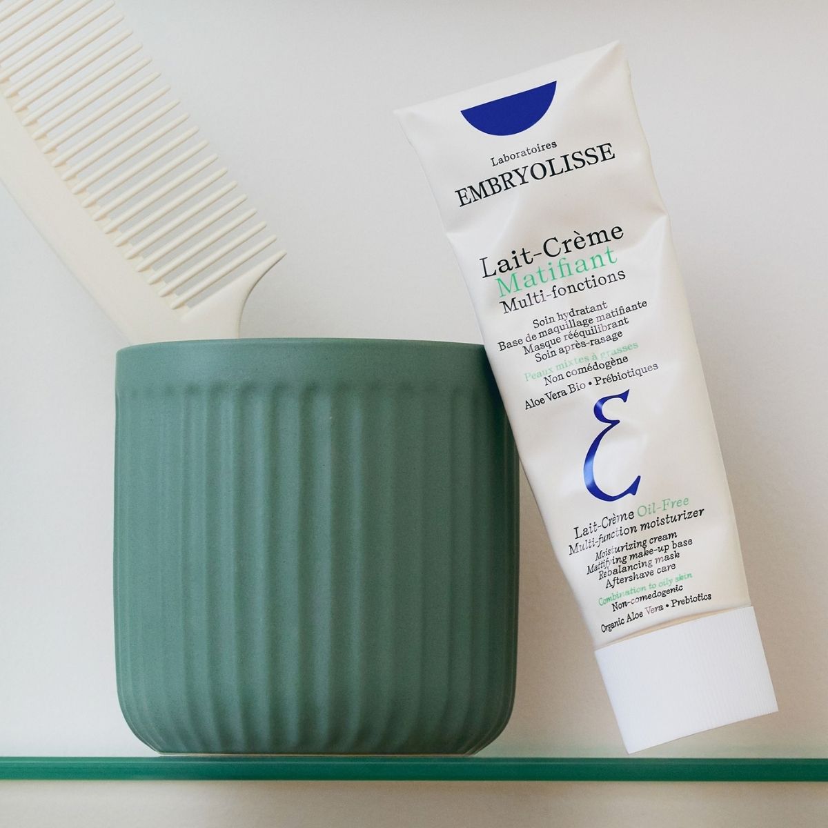 Lait-Crème Oil-Free tube on a bathroom shelf with a green cup and a comb, part of a daily routine