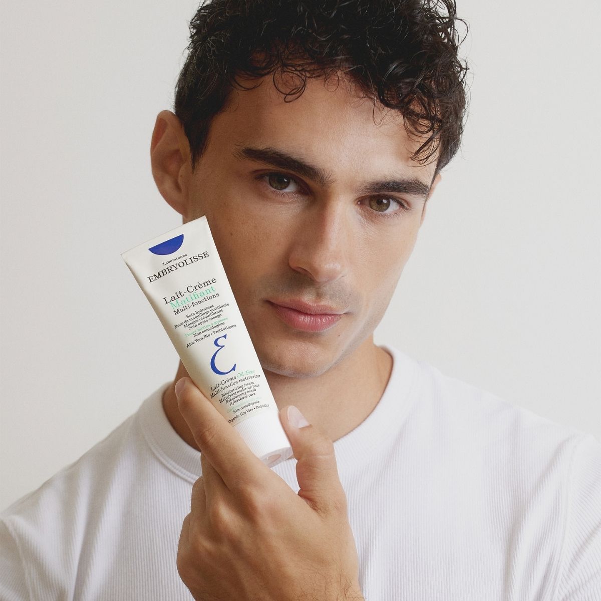 A man holds the Lait-Crème Oil-Free tube beside his face, skin left matte and shine-free