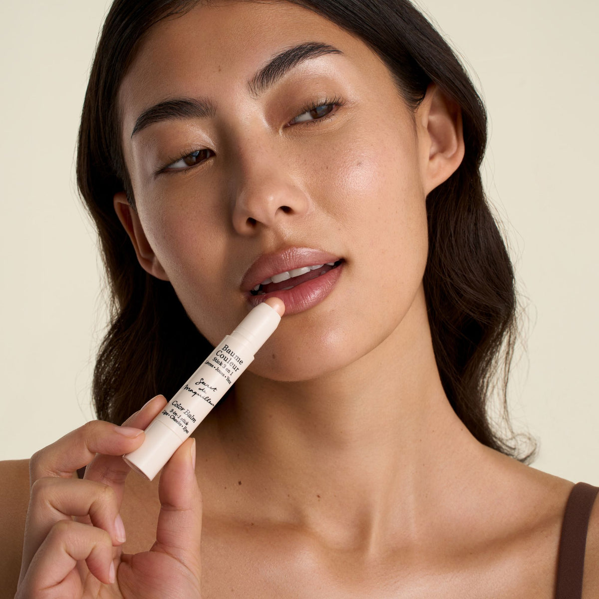 Model applying the Color Balm 3-in-1 Stick in Champagne to the lips for a soft satin shine